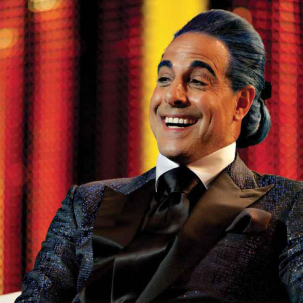 Stanley Tucci as Caesar Flickerman, the charismatic host of the Hunger Games in the film series
