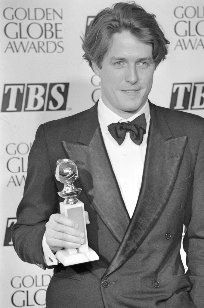 Hugh Grant holding his Golden Globe award