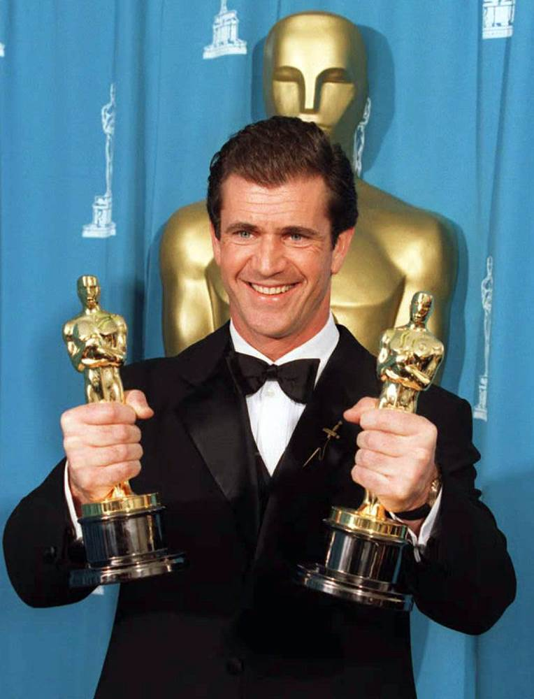 Mel Gibson holding two Academy Awards