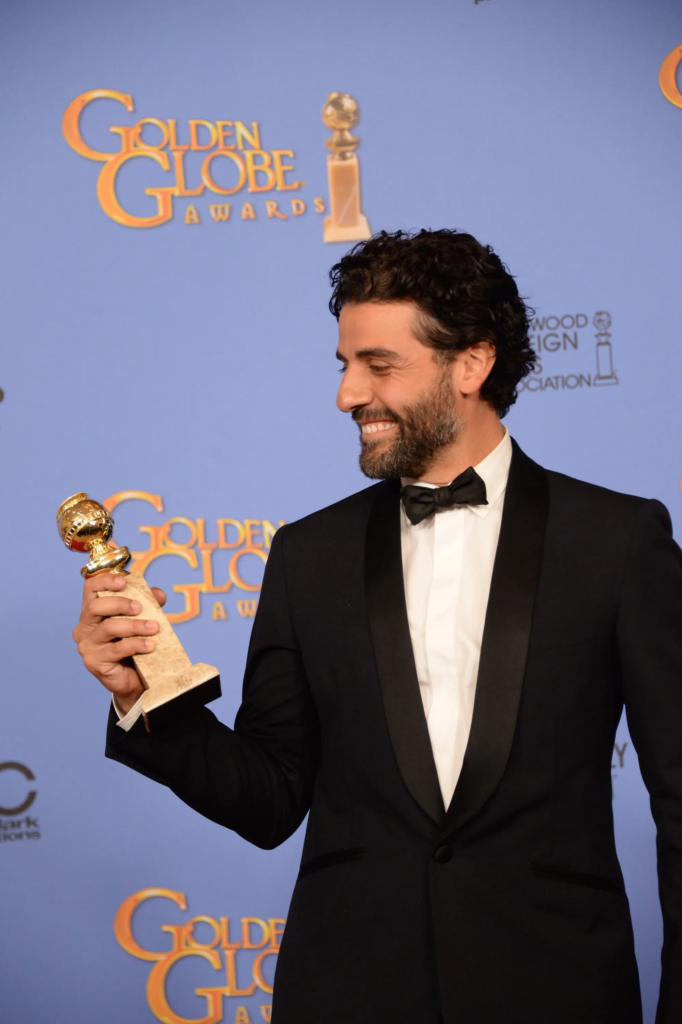 Oscar Isaac holding his Golden Globe award