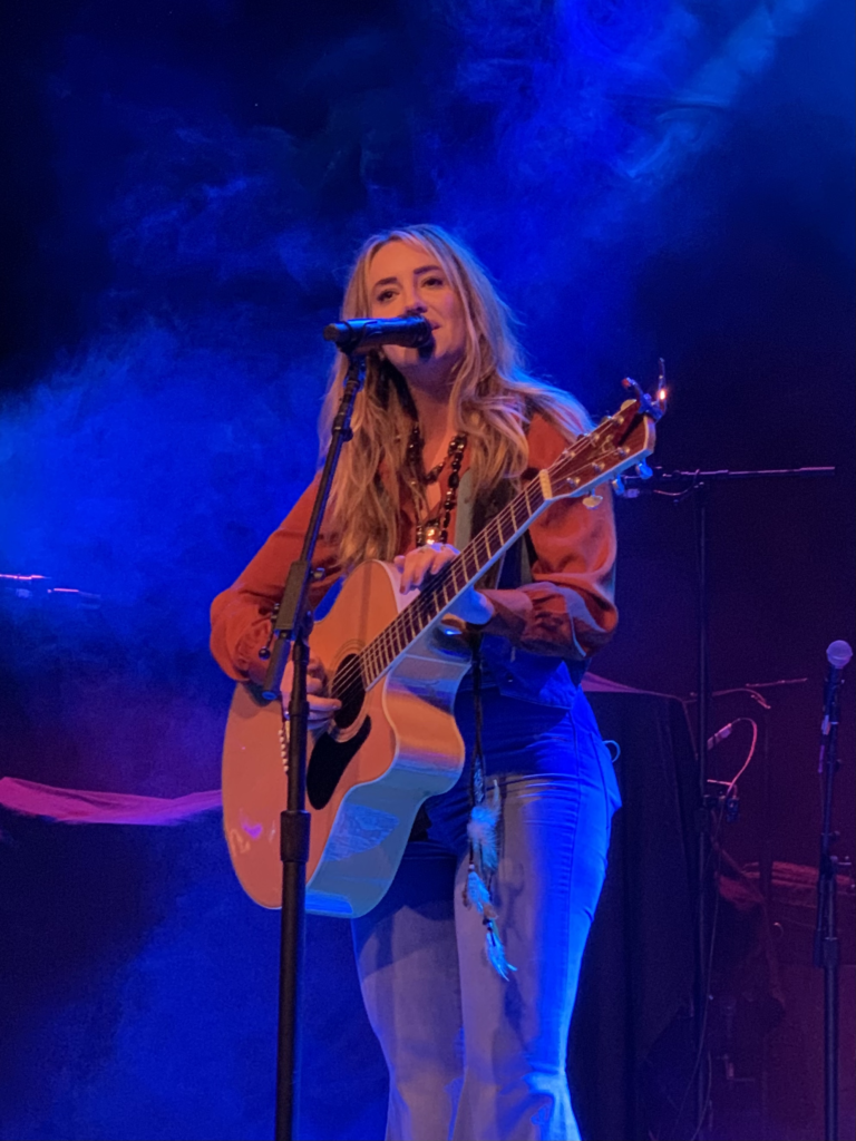 Lainey Wilson performing live on stage with her guitar