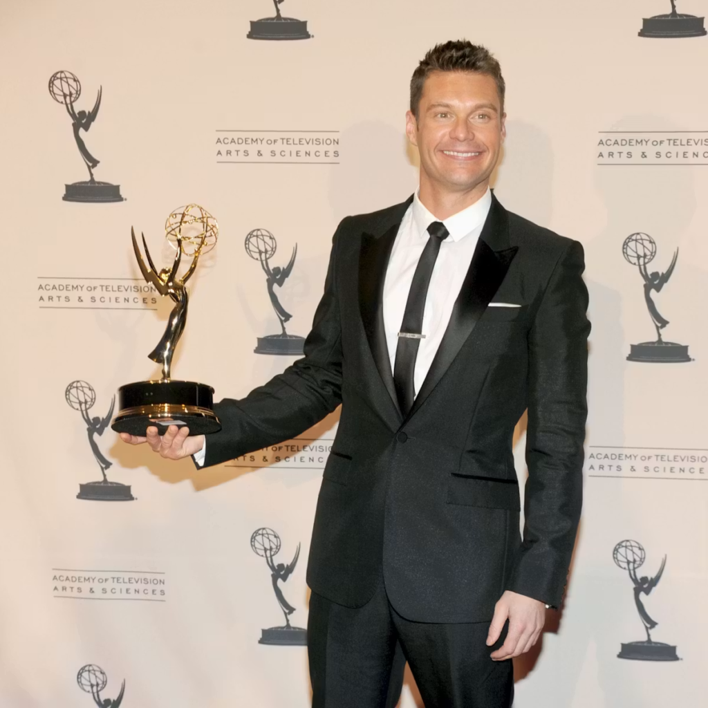 television personality and producer Ryan Seacrest posing with an Emmy Award