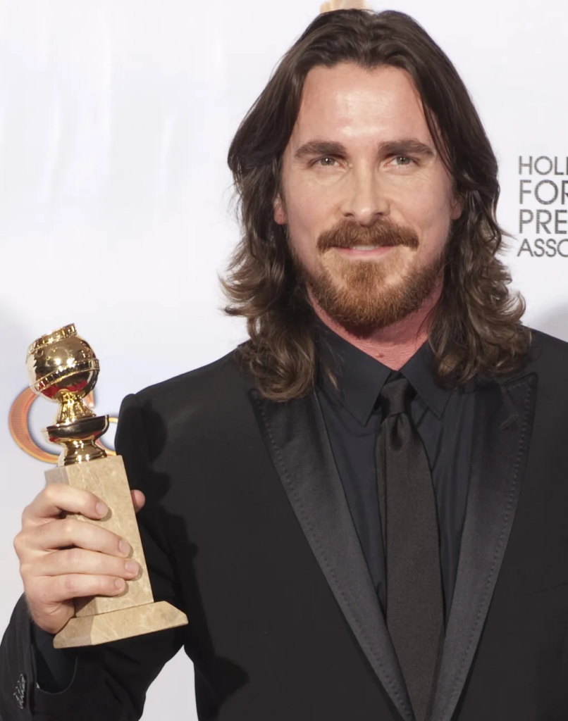 Christian Bale holding a Golden Globe award