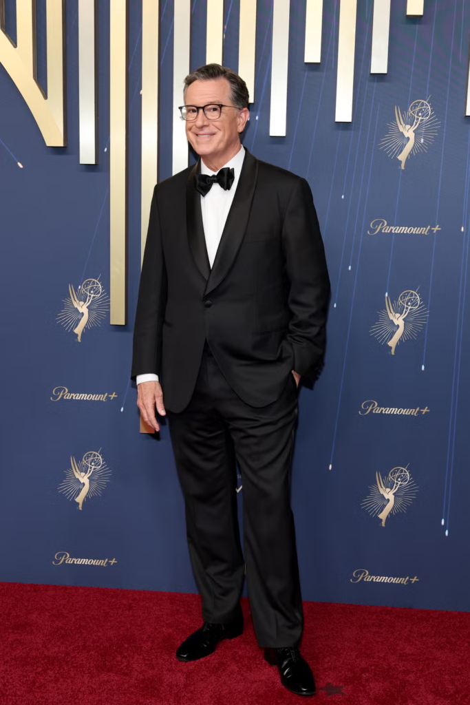 Stephen Colbert wearing a classic black tuxedo on a red carpet at the 2025 Emmy Awards