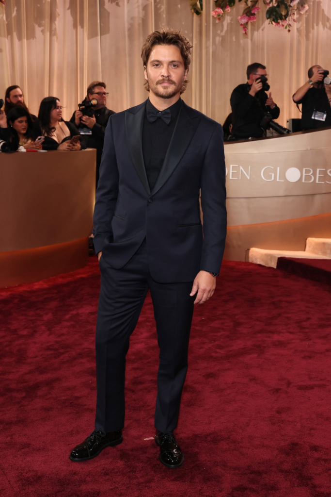 Luke Grimes wears a structured dark suit with a slim-fit dark dress shirt at the 2026 Golden Globes