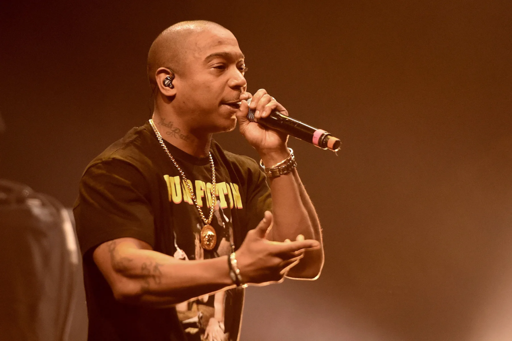 Ja Rule performing on stage while wearing a black t-shirt and gold necklace