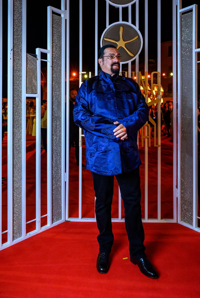 Steven Seagal wears a statement blue satin-like quilted jacket featuring a traditional collar on the red carpet