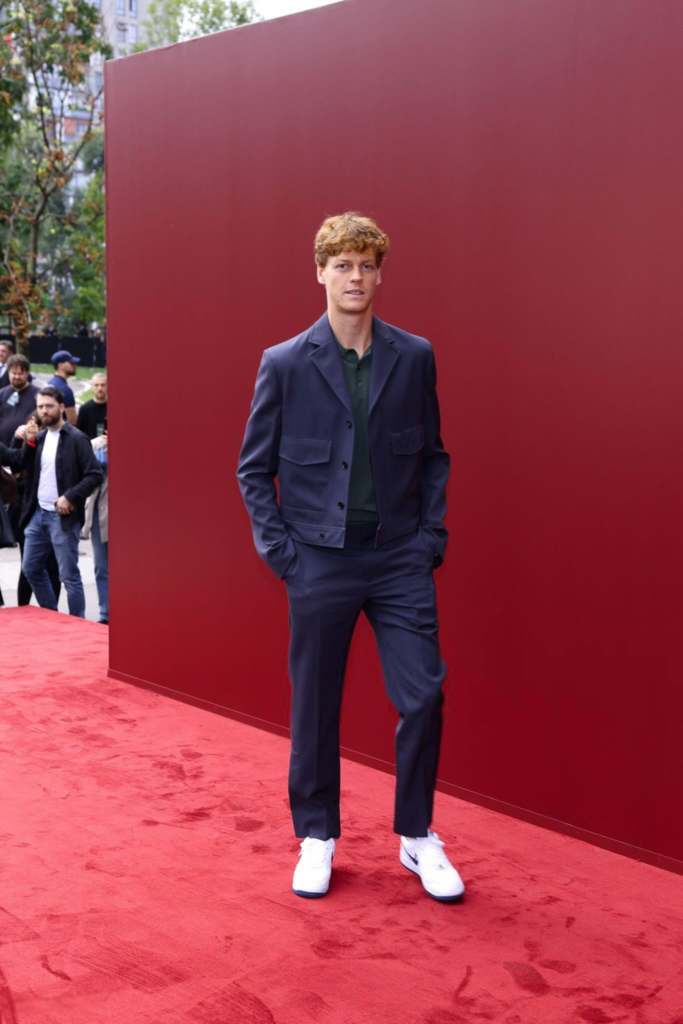 Jannik Sinner is pictured wearing a navy blue Gucci suit paired with white Nike sneakers at the Spring/Summer 2025 show during Milan Fashion Week