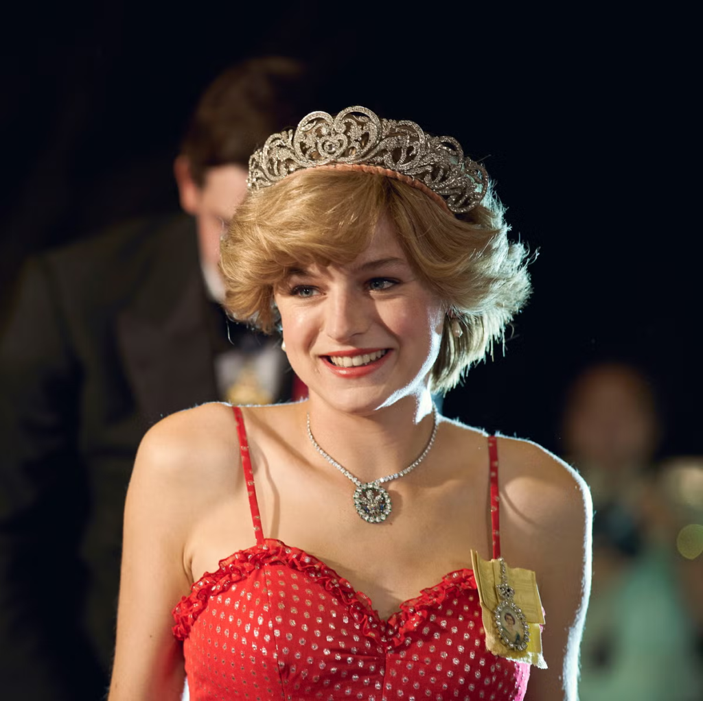 Emma Corrin portraying Diana, Princess of Wales, wearing a red polka-dot dress and a tiara in a scene from the fourth season of the Netflix series The Crown