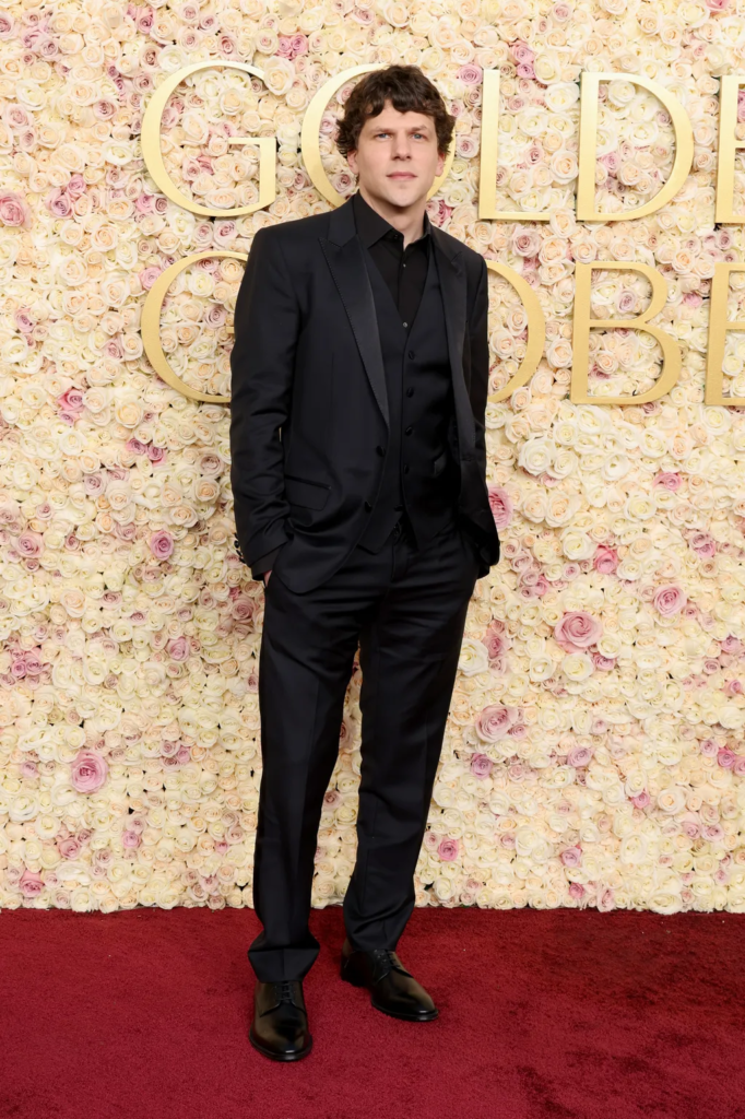 Jesse Eisenberg poses in an all-black suit on the red carpet at the 82nd Golden Globe Awards