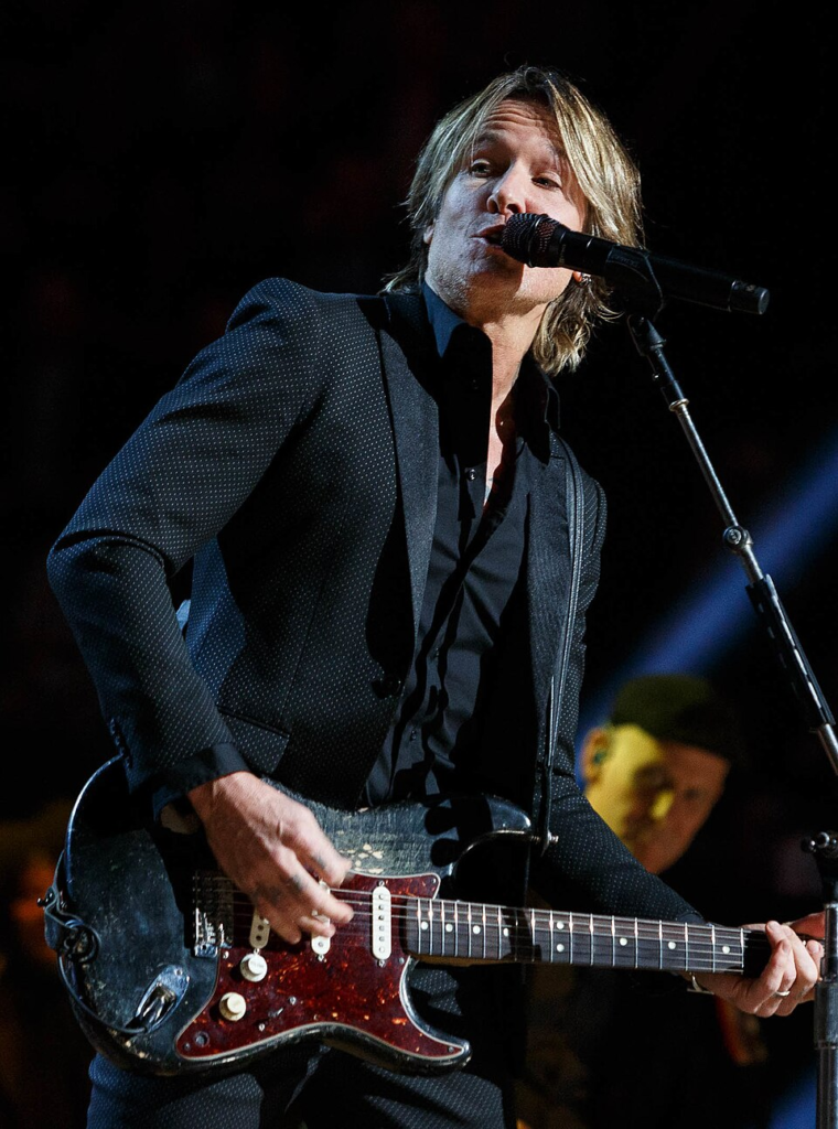 Keith Urban performing live with a black Fender Stratocaster electric guitar