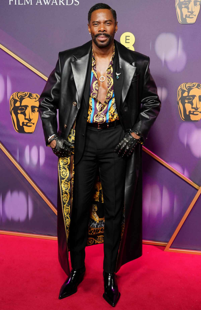 Colman Domingo wears a long black Versace leather coat with patterned lining over a matching printed shirt at the 2025 British Academy Film Awards