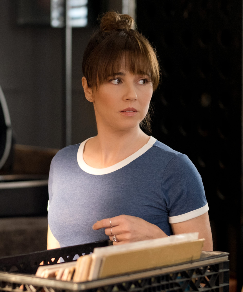 Linda Cardellini plays Judy Hale, wearing a blue ringer t-shirt in this scene from Dead to Me
