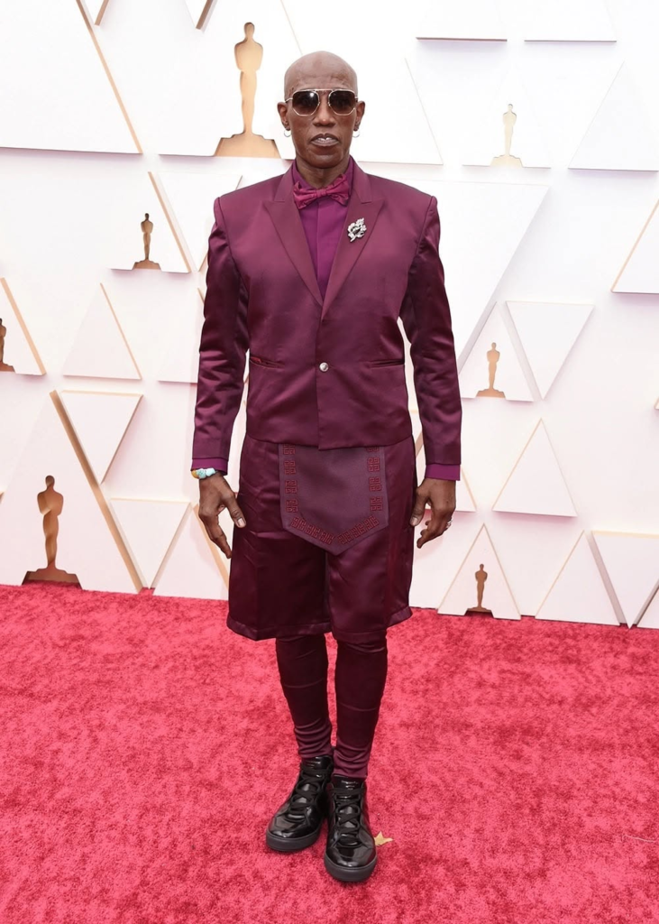 Wesley Snipes wears a burgundy Givenchy tuxedo featuring Bermuda shorts and matching leggings at the 2022 Academy Awards