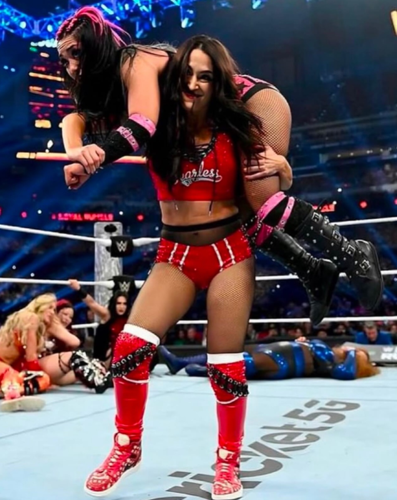 former WWE superstar Nikki Bella performing a wrestling move on Roxanne Perez during a match at the Royal Rumble 2025 event