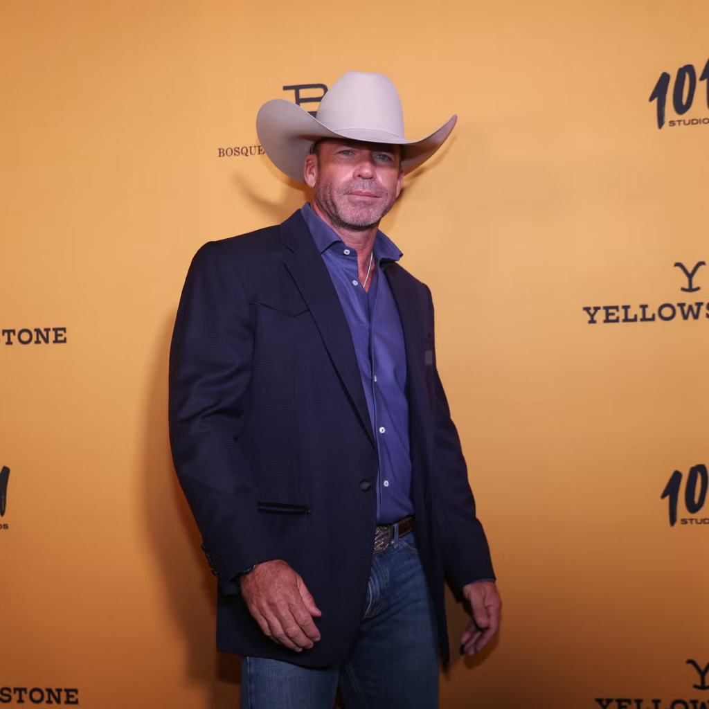 Taylor Sheridan wearing a distinct light-colored cowboy hat and a dark blazer