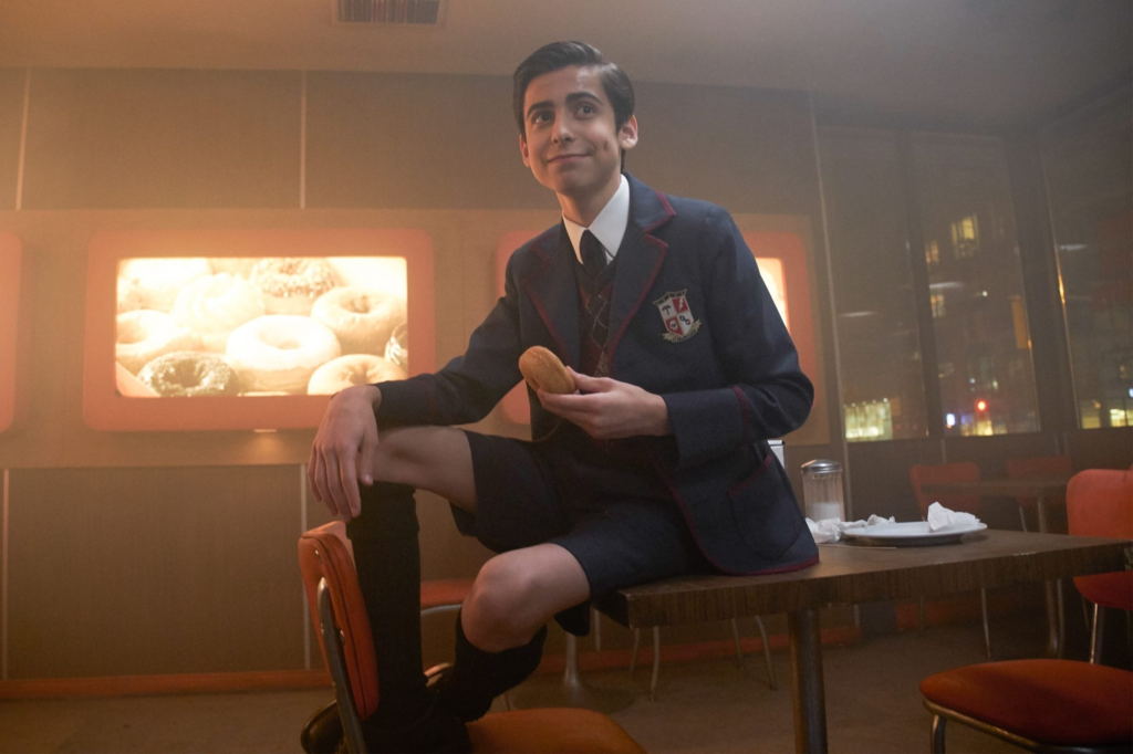 Aidan Gallagher as Number Five wearing the iconic Umbrella Academy school uniform blazer and shorts