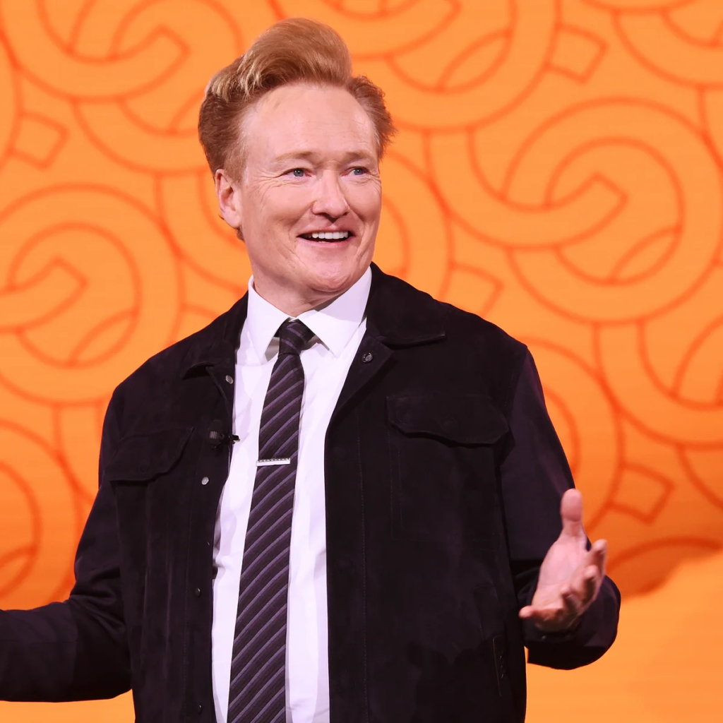 American comedian, writer, and television host Conan O'Brien speaking on stage at a WarnerMedia event