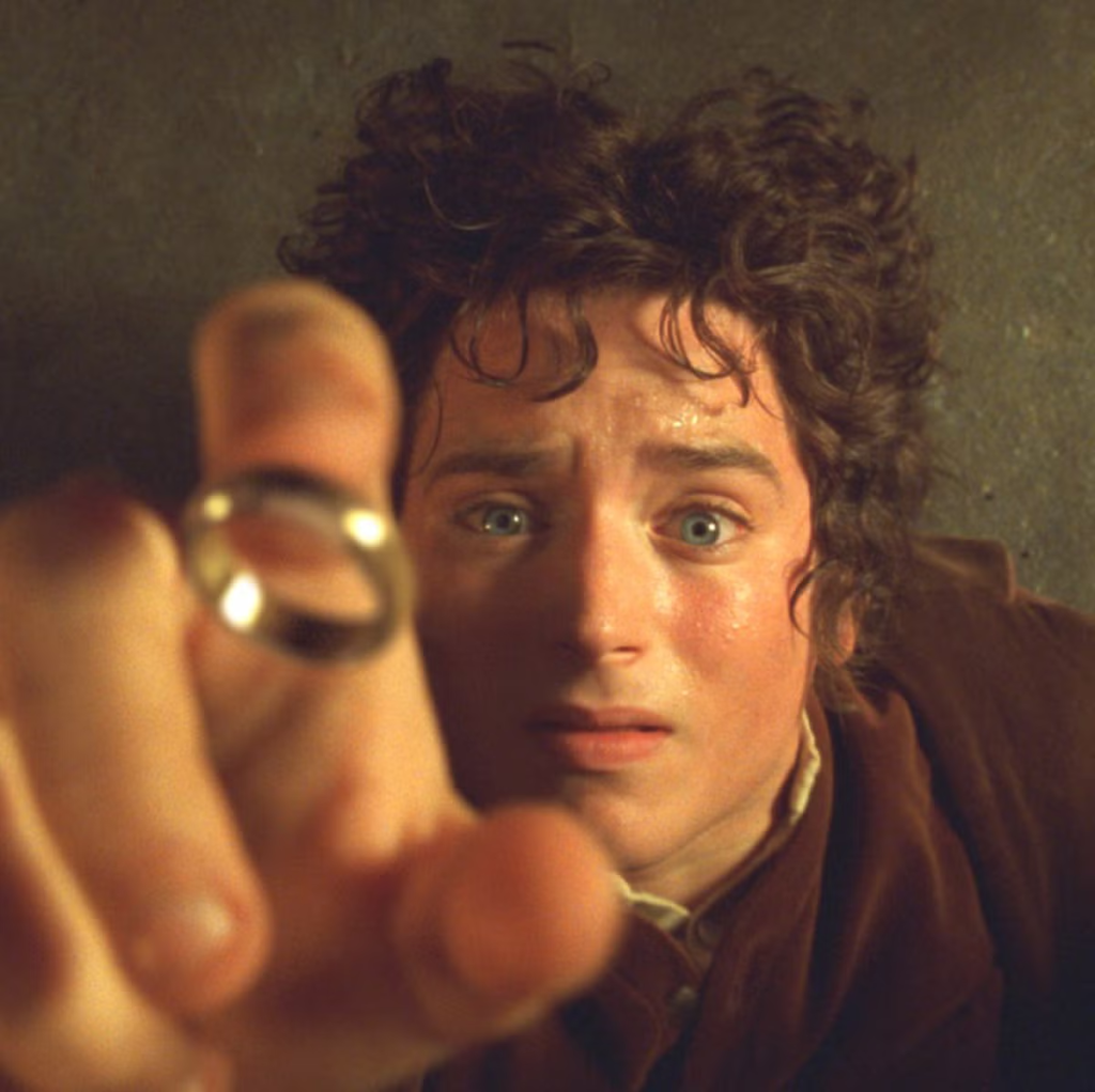 Elijah Wood as the hobbit Frodo Baggins reaching out with the One Ring in the epic fantasy film The Lord of the Rings: The Fellowship of the Ring (2001)