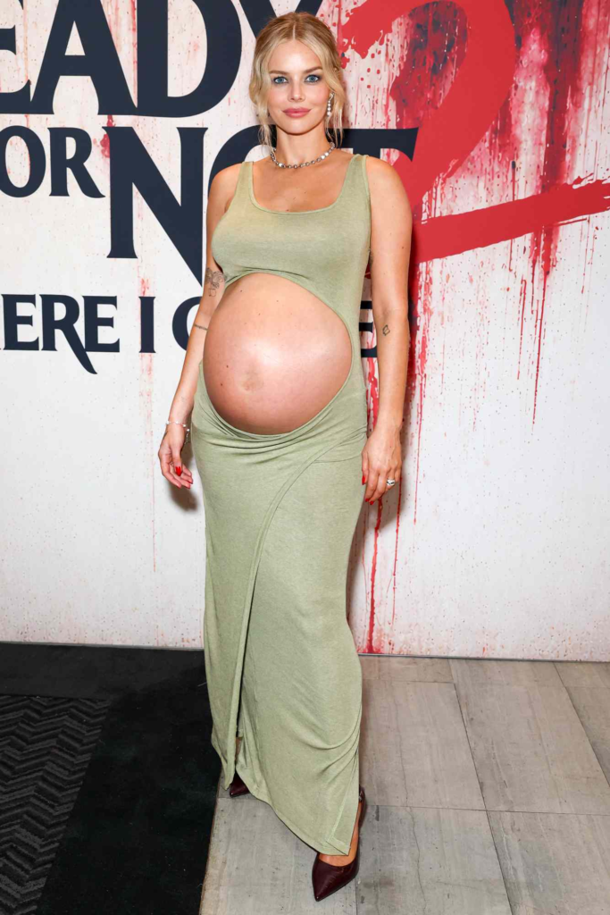 Actress Samara Weaving on the red carpet in an olive green cut-out maxi dress while showcasing her baby bump at a Los Angeles screening for Ready or Not 2: Here I Come on March 16, 2026