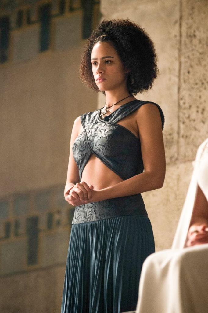 Nathalie Emmanuel portraying Missandei in a light blue halter-neck dress with a textured metal belt on Game of Thrones