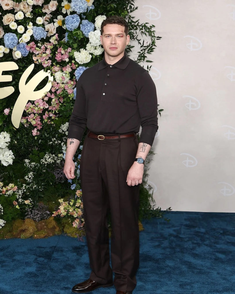 Oliver Stark attended the 2025 Disney Upfront in New York City, styled in a dark long-sleeved polo shirt and brown trousers