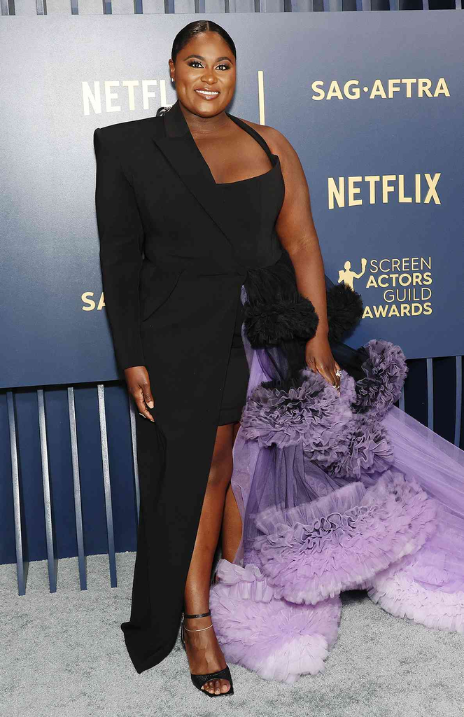 actress Danielle Brooks wearing a black one-sleeve blazer-style gown with a dramatic tiered purple tulle train at the 30th Screen Actors Guild Awards