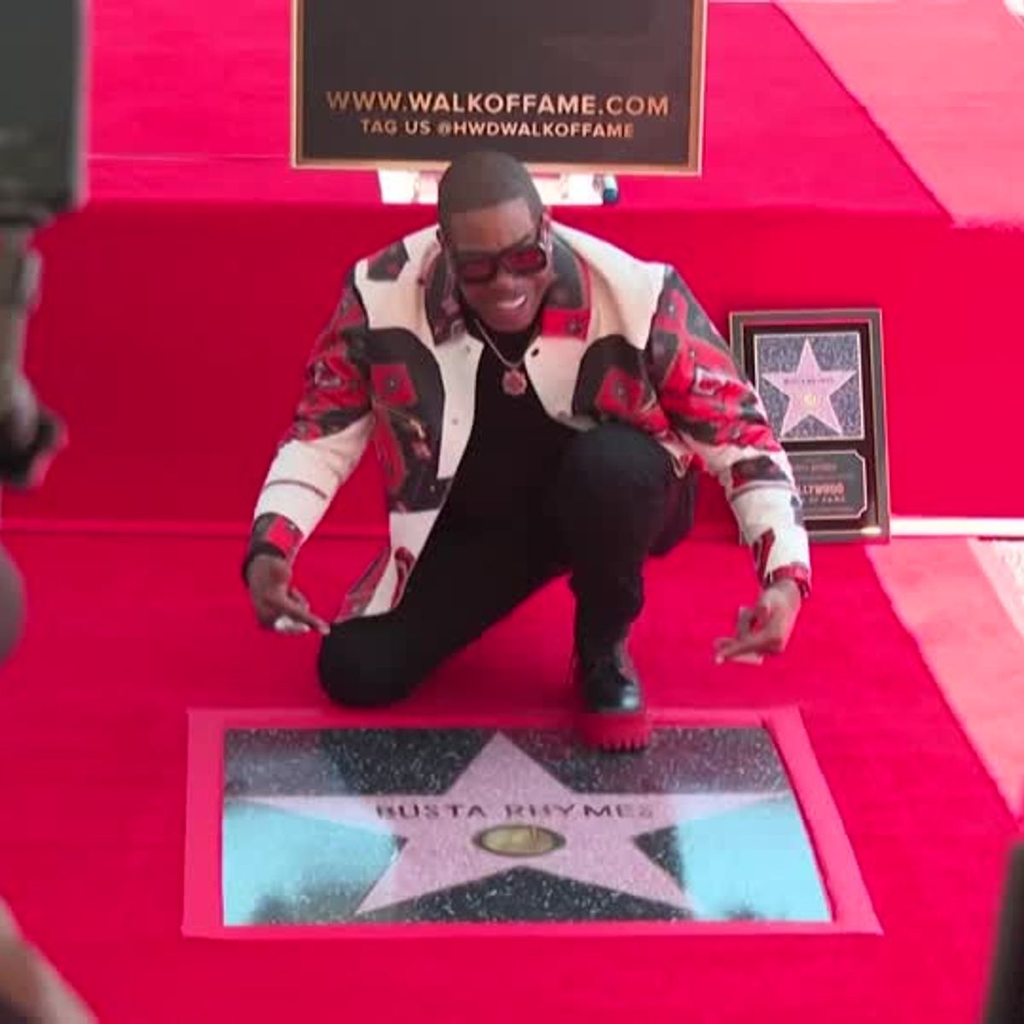 Rapper and actor Busta Rhymes crouches beside his newly unveiled star on the Hollywood Walk of Fame