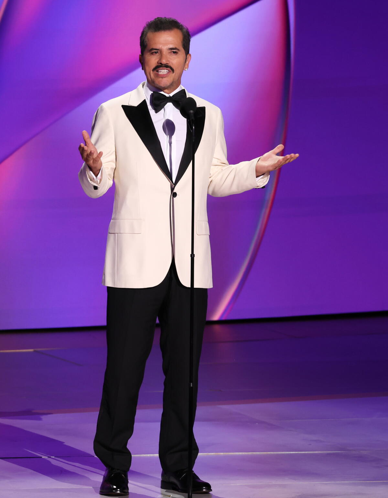 Actor John Leguizamo wears a white tuxedo jacket with a black shawl lapel and bow tie while speaking on stage at the 76th Primetime Emmy Awards on September 15, 2024