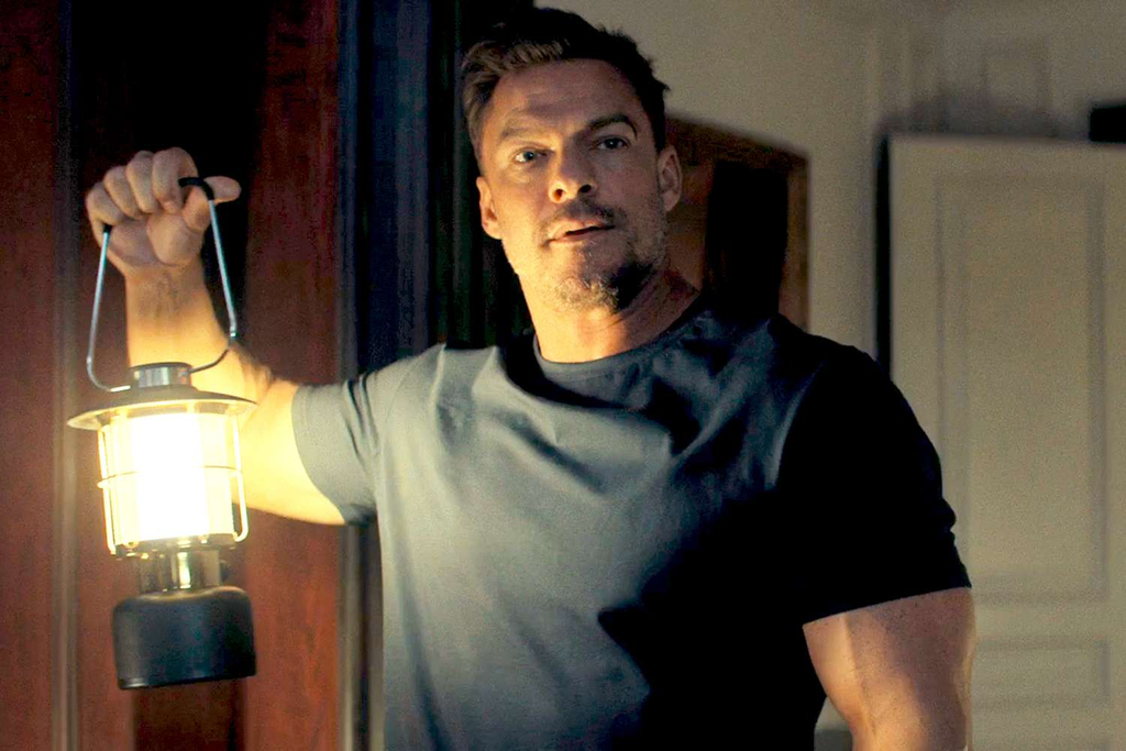 Alan Ritchson appears as the title character Jack Reacher holding a lantern in the action-thriller series Reacher on Prime Video