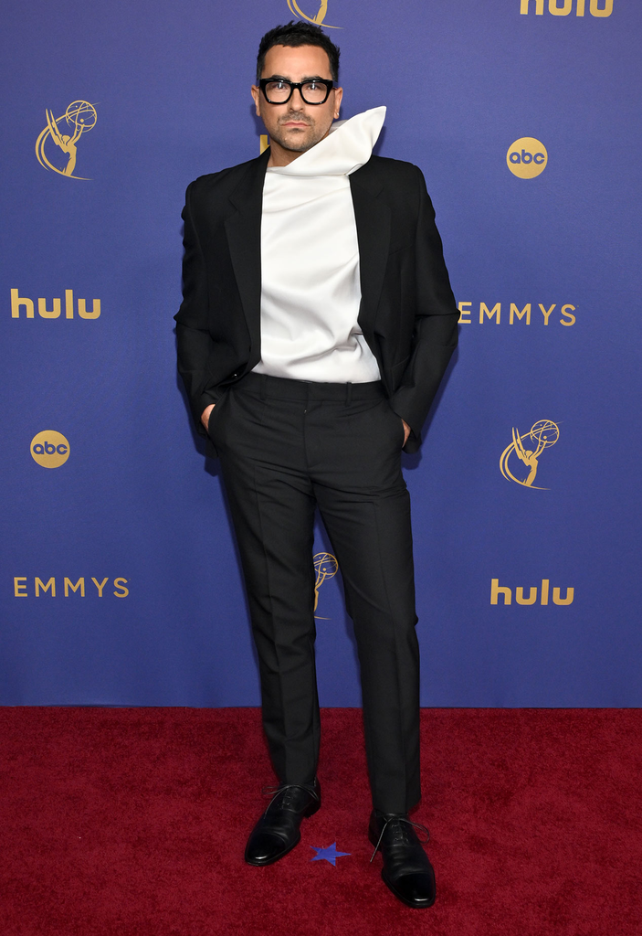 Actor and writer Dan Levy wears a black suit from the Loewe Spring/Summer 2025 menswear collection paired with a sculptural off-white silk scarf top at the 76th Primetime Emmy Awards