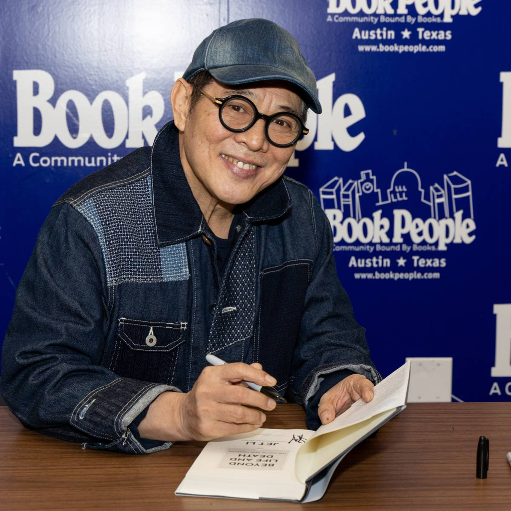 Jet Li smiling while signing a book